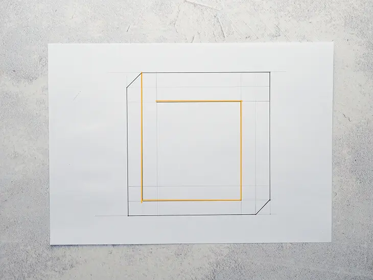 Ein gezeichnetes Quadrat mit orangener Innenlinie auf einem weißen Blatt. Foto: Johanna Rundel