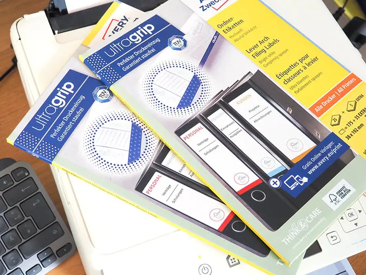 Auf einem Drucker liegen zwei Packungen Ordnerrücken-Etiketten von Avery Zweckform. Foto: Johanna Rundel
