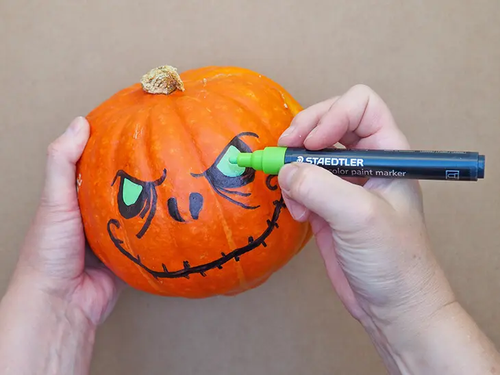 Jemand malt die Augen eines Halloween-Kürbis mit einem grünen Marker von STAEDTLER aus. Foto: Johanna Rundel