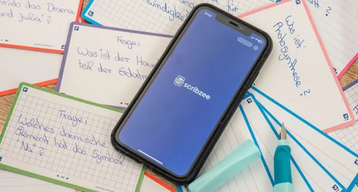 Auf vielen Notizzetteln liegt ein Smartphone, auf dem die App Scribzee von Oxford geöffnet ist