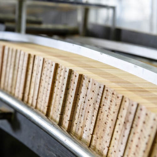 Holzfassungen für Bleistiftminen sind aneinandergereiht in einer Maschine.