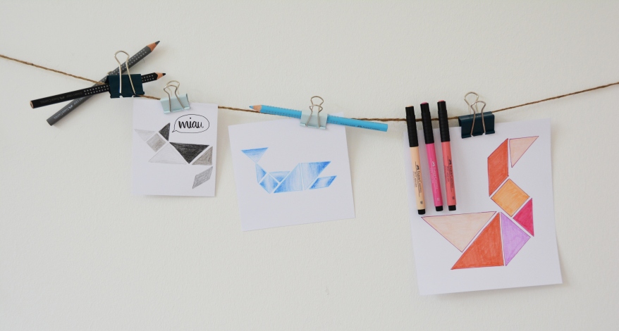 Tangram-Bilder an Schnur mit Stiften befestigt