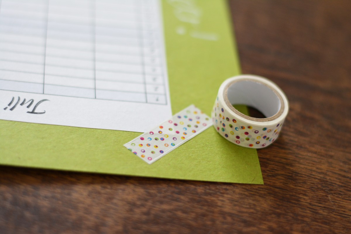 Bunt gepunktetes Washi-Tape dekoriert Planer auf grünem Karton.