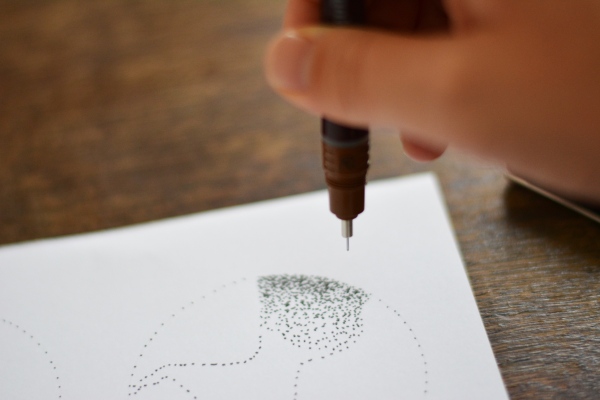 Hand setzt Punkte mit einem Rapidograph von Rotring auf Papier