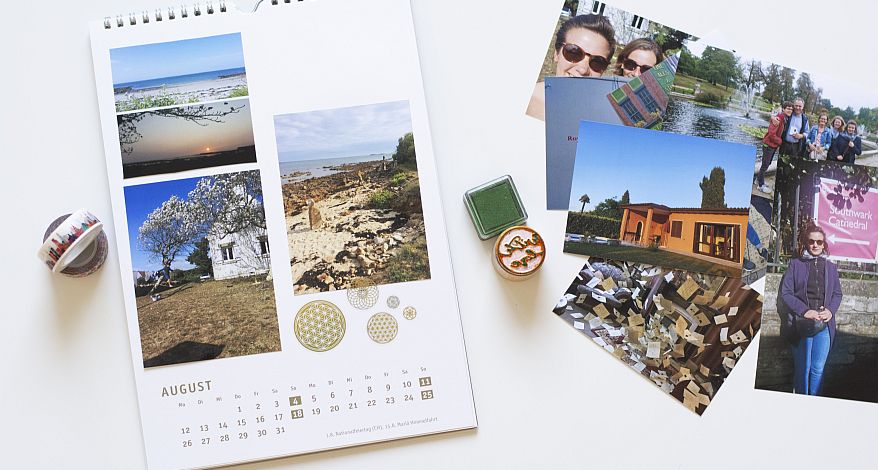 Neben einem selbstgestalteten Fotokalender von Heye liegen weitere Fotos sowie Washitape und Stempel.