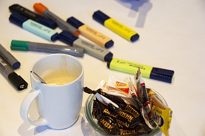 Kaffee, Süßigkeiten und Textmarker auf einem Tisch.