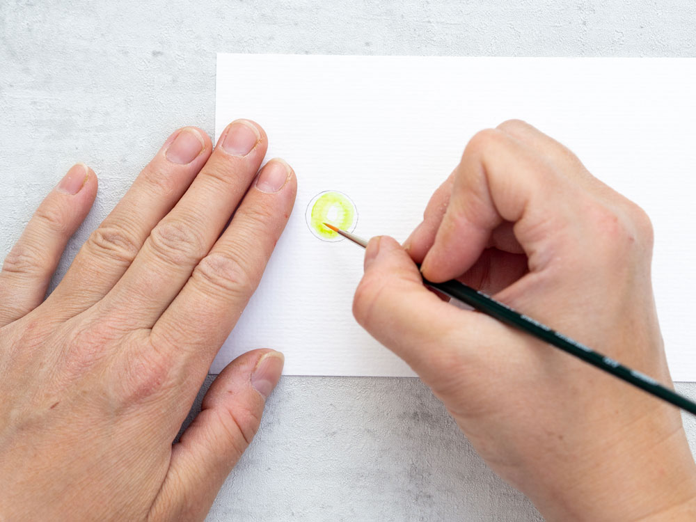Feiner Pinsel malt gelben Kreis auf Papier