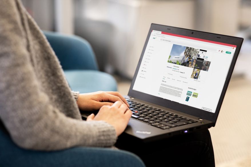 Person hat einen aufgeklappten Laptop auf dem Schoss und tippt