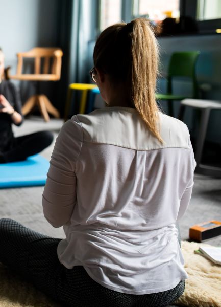 rau sitzt im Schneidersitz auf Teppich und macht Yoga