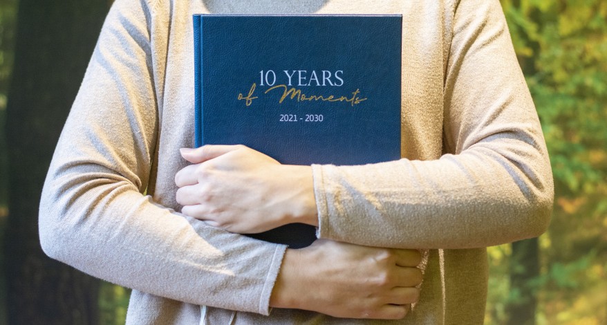 Nahaufnahme einer Person, die einen 10 Jahreskalender der Marke BRUNNEN vor der Brust umschlungen hält.