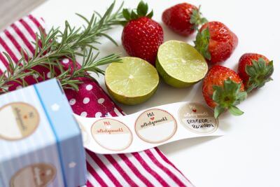 Etikettenrolle, daneben Erdbeeren, Limetten und Kräuter