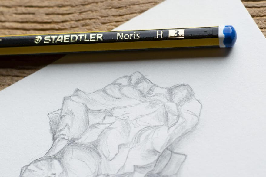 Ein Bleistift Noris der Marke Staedtler liegt auf einem Blatt Papier, auf das eine Muschel gezeichnet ist.