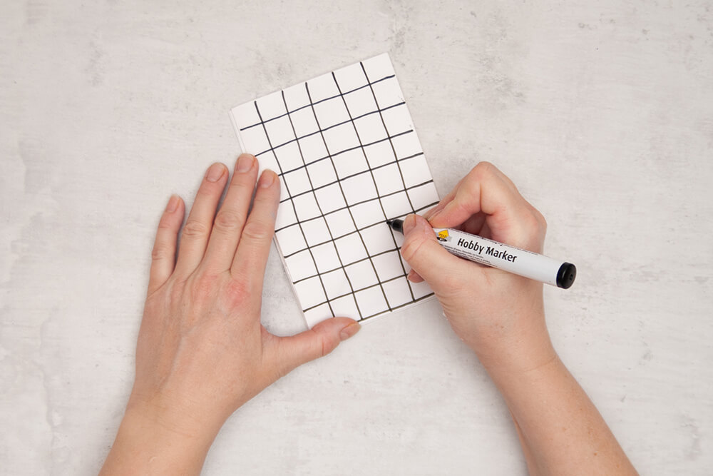 Eine Papiertüte von Knorr-Prandell wird mit einem schwarzen Hobbymarker mit einem Gittermuster bemalt. Fotos: Johanna Rundel