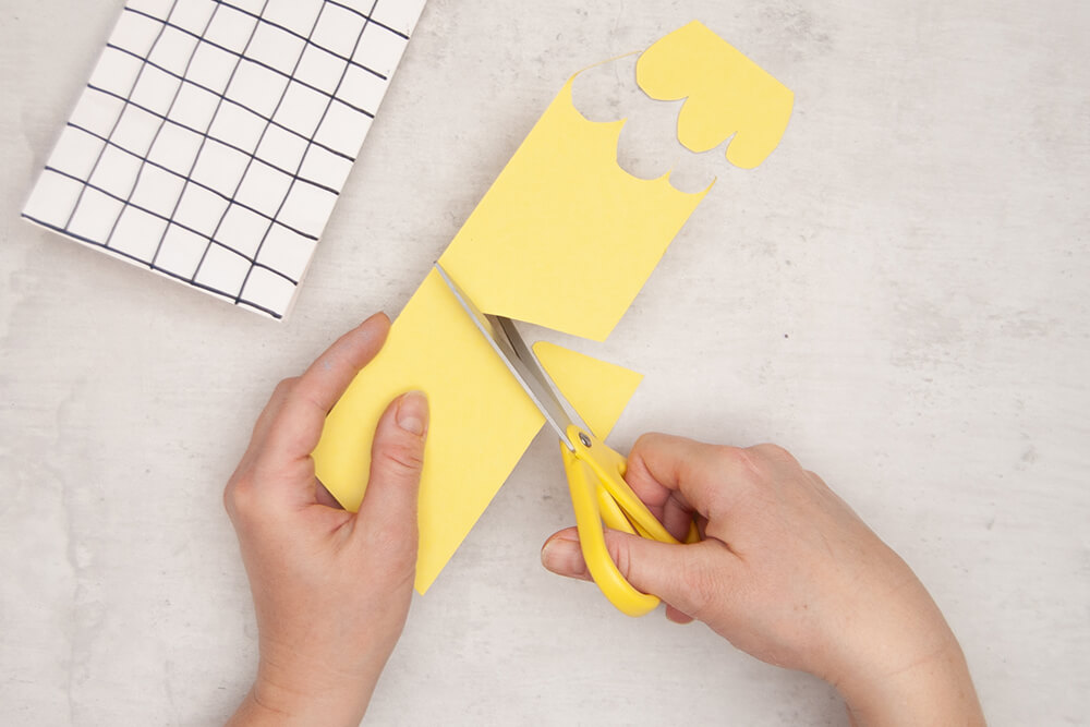 Aus gelbem Fotokarton werden ein Schnabel und ein Kamm für ein Huhn ausgeschnitten. Im Hintergrund liegt eine bemalte Papiertüte von Knorr-Prandell. Fotos: Johanna Rundel