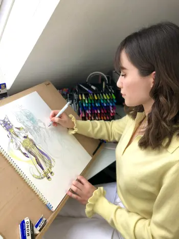 Eine Frau sitzt an einem Zeichnbrett und coloriert ein Manga.