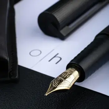 Ein schwarzer Füller mit goldener Feder von Otto Hutt liegt auf einem weißen Blatt Papier mit dem Monogramm O.H.