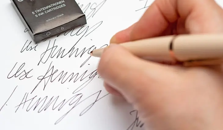 Jemand übt auf einem weißen Blatt Papier seine Unterschrift mit einem Füller von Otto Hutt zu schreiben. Foto: Johanna Rundel