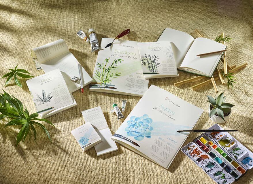 Blöcke der Papierserie Natural Line von Hahnemühle, umgeben von Künstlermaterial.
