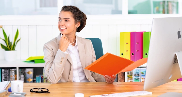 Frau im Büro mit Neon Sammelmappe von HERMA in der Hand.
