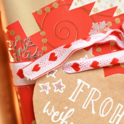 Detail einer Geschenkverpackung mit Herzanhänger und Schleife.