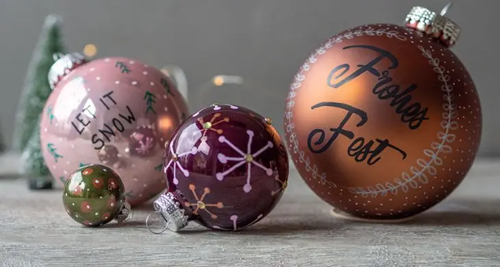 4 Weihnachtskugel auf dem Tisch mit der Schrift Frohes Fest, Let it snow...