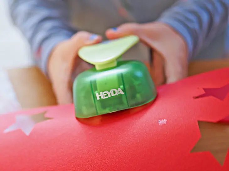 Ein Kind stanzt mit HEYDA Stanzer einen Stern aus Tonpapier aus. Foto: Johanna Rundel