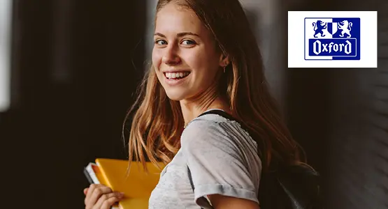 Eine junge Frau hält einen Collegeblock von Oxford in der Hand und blickt lächelnd in die Kamera. Rechts oben ist das Logo von Oxford abgebildet.