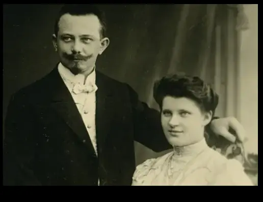 Schwarz weiß Foto eines Mannes mit Schnurbart, der neben der Sekretärin Elsa Tesmer steht, beide in der Kleidung des frühen 20. Jahrhunderts“. 