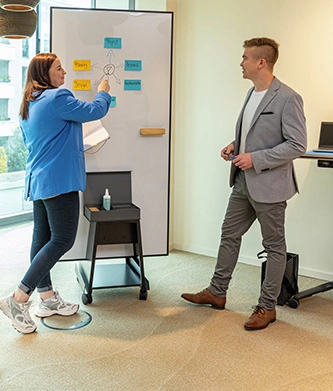 Zwei Personen arbeiten an mobilem Whiteboard im Büro.