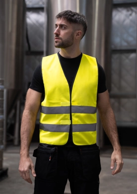 Mann trägt eine gelbe Warnweste für seine Sicherheit in einer industriellen Umgebung.