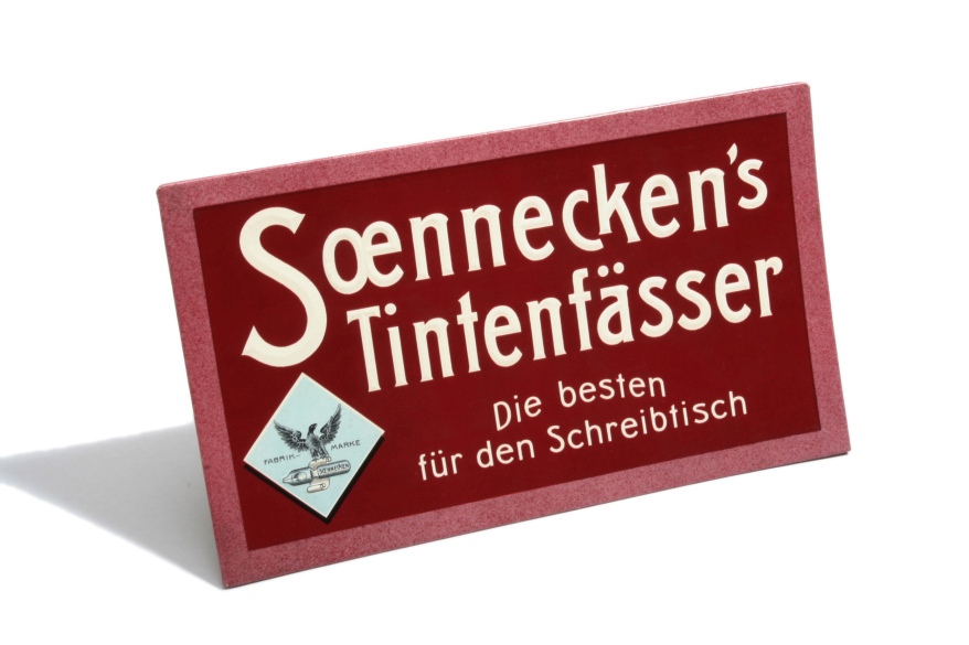 Abbildung eines Schildes auf dem steht "Soennecken's Tintenfässer. Die besten für den Schreibtisch".