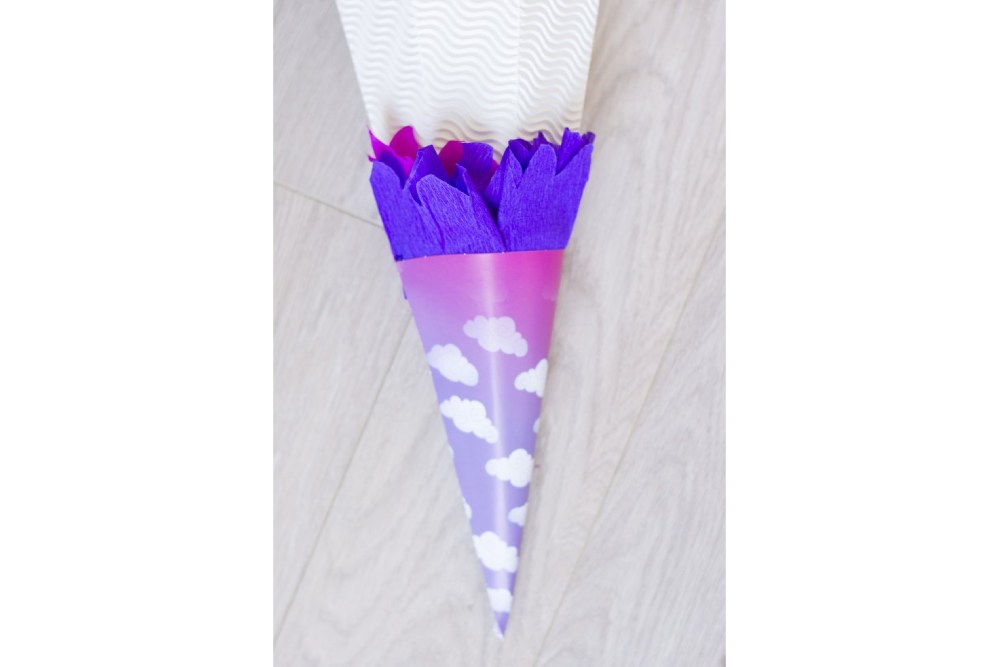 Kleine lila-pinke Papiertüte mit lila Krepppapier am Rand.