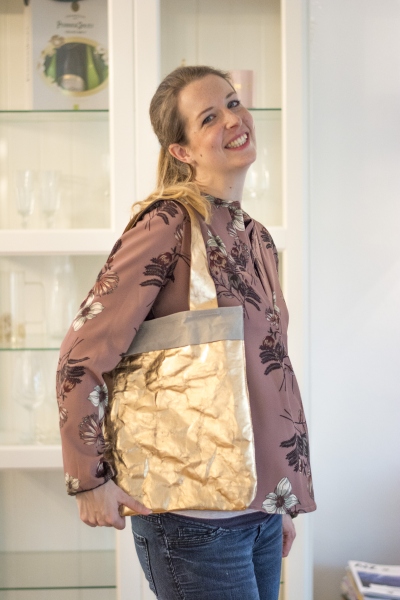Frau präsentiert selbstgenähte goldene SnapPap-Tasche mit Stolz