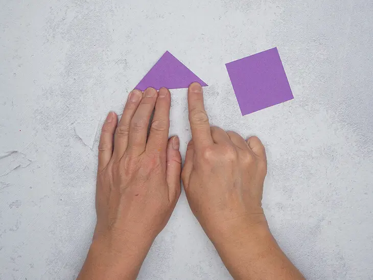 Jemand faltete ein kleines, lila Papierquadrat zu einem Dreieck. Foto: Johanna Rundel