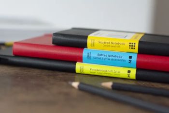 Seitlicher Blick auf drei aufeinander gestapelte Notizbücher von Moleskine. 