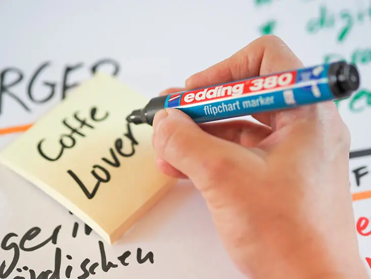Jemand schreibt mit einem edding-Marker auf ein Post-It. Foto: Johanna Rundel