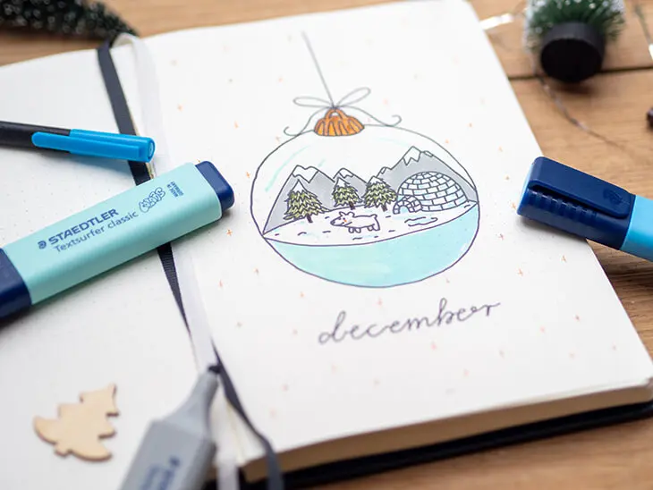 BuJo-Deckblatt mit Schneekugelmotiv darauf liegen STAEDTLER-Marker. Foto: Johanna Rundel