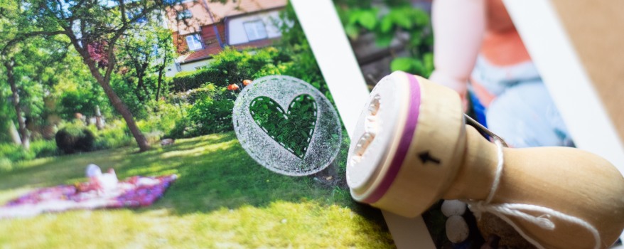 Nahaufnahme eines Stempels mit dem Motiv eines Herz, das auf ein Foto gestempelt wurde. 