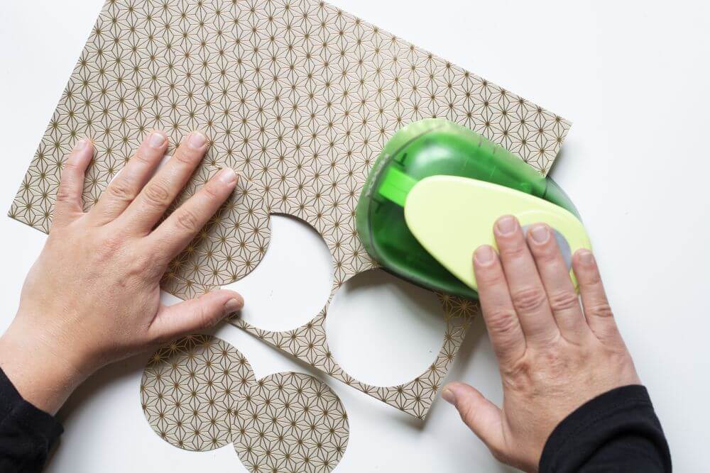 Mit Hilfe eines Motivstanzers werder Kreise aus Motivkarton ausgestanzt.