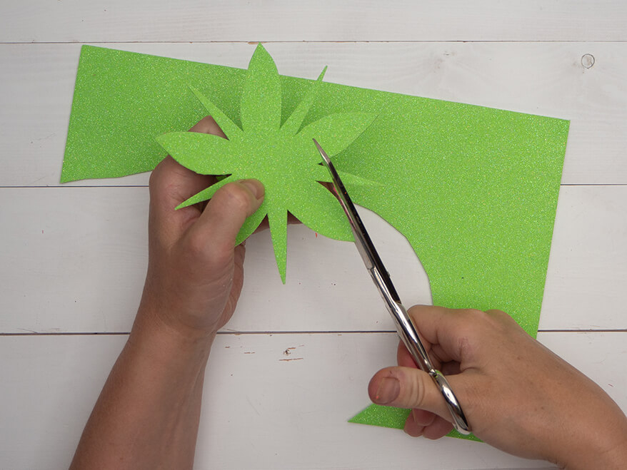 Jemand schneidet mit einer Schere aus einem hellgrünen Moosgummi von Knorr Prandell, Blätter aus. Der Untergrund ist hell. Foto: Johanna Rundel