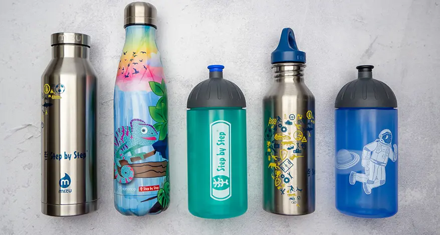 Auf einem hellgrauen Untergrund in Betonoptik liegen fünf verschiedene Trinkflaschen von Step by Step nebeneinander. Foto: Johanna Rundel