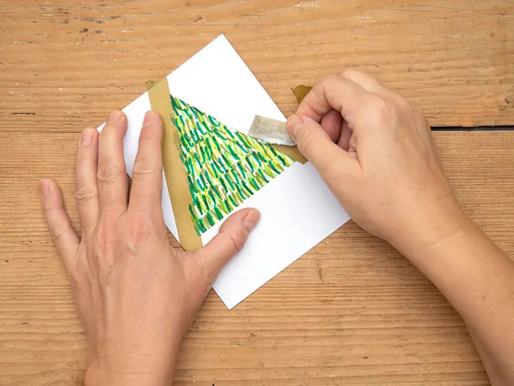 Jemand zieht ein Klebeband-Dreieck von einer Klappkarte ab. Foto: Johanna Rundel
