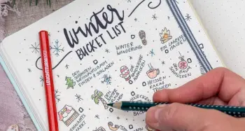 In ein Bullet Journal ist eine kreativ verzierte Seite für eine Winter Bucket List abgebildet.