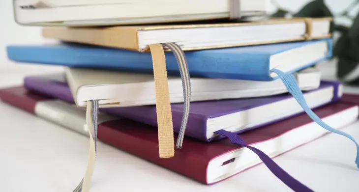 Mehrere Notizbücher von LEUCHTTURM1917 in unterschiedlichen Farben liegen übereinander gestapelt.