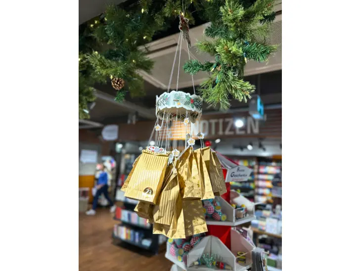 Ein Kranz behangen mit Adventskalendertüten hängt von der Decke.