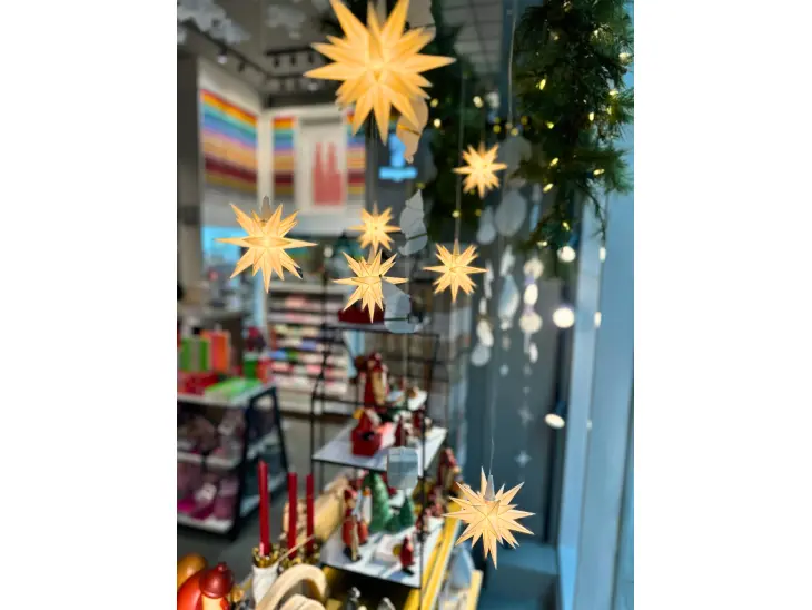 Weiße Herrnhuter Sterne in verschiedenen Größen hängen in einem Schaufenster.