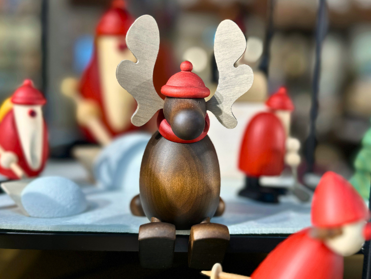 Ein Elch aus Holz mit roter Mütze und Schaal.
