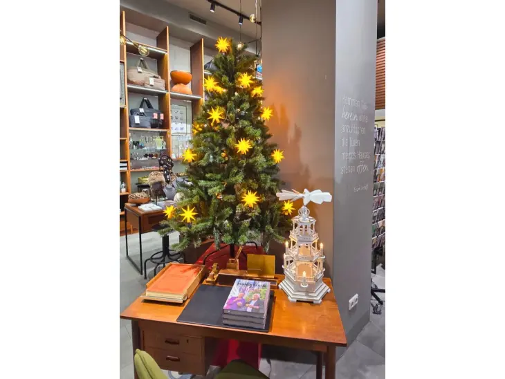 Ein Holztisch auf dem ein Weihnachtsbaum und eine Weihnachtspyramide steht.