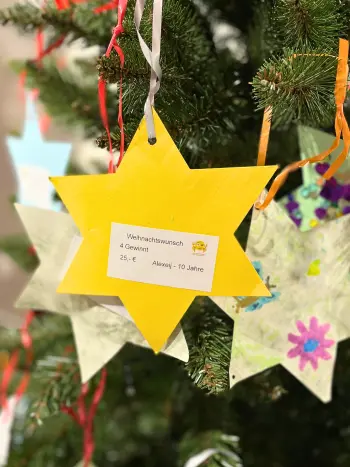 Ein gebastelter Stern mit Wunsch an einem Weihnachtsbaum