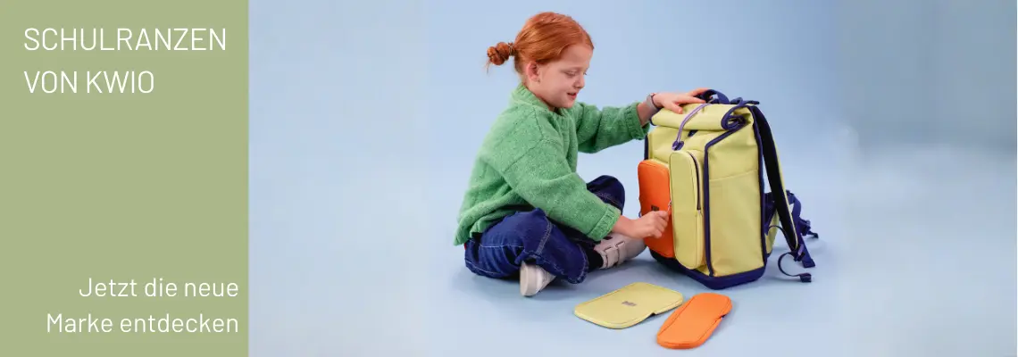 Ein Kind sitzt im Schneidersitz auf dem Boden und öffnet gerade einen Schulranzen von KWIO.